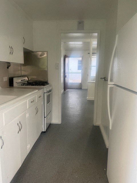 a kitchen with a white refrigerator freezer next to a stove top oven